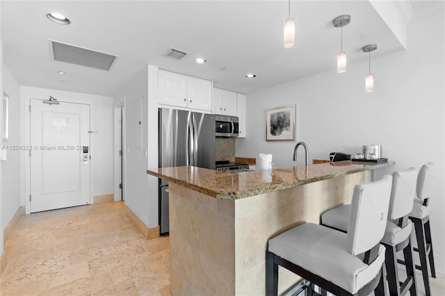 kitchen featuring kitchen peninsula, white cabinets, stainless steel appliances, and decorative light fixtures