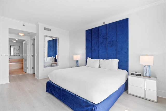 bedroom featuring light wood-type flooring, ornamental molding, and ensuite bath