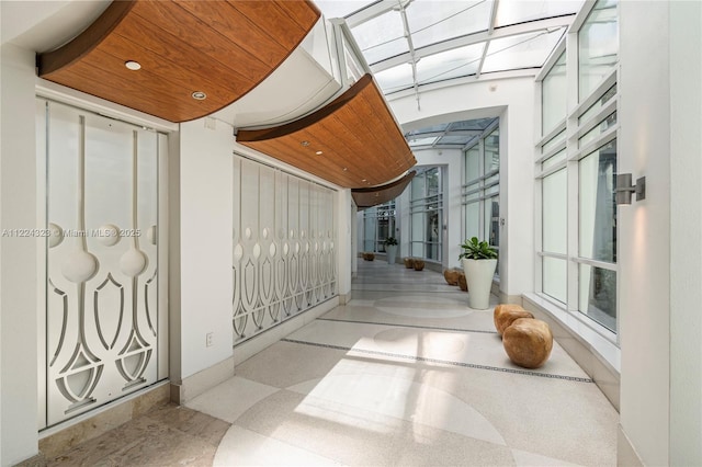 hallway with a towering ceiling and wooden ceiling