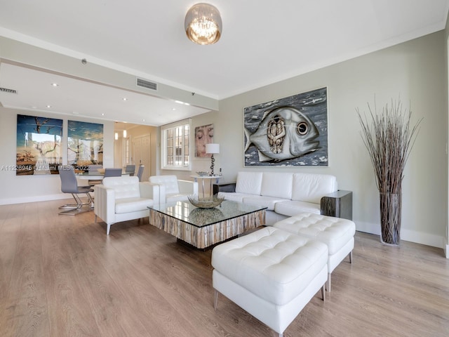 living room featuring a chandelier, ornamental molding, and light hardwood / wood-style floors