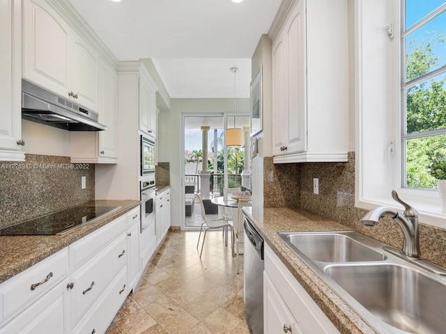 kitchen with sink, backsplash, stainless steel appliances, decorative light fixtures, and white cabinetry