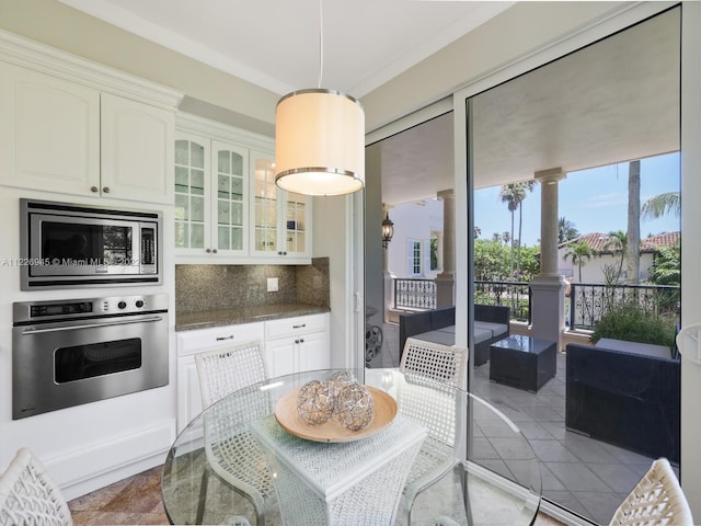 kitchen with hanging light fixtures, backsplash, light tile flooring, appliances with stainless steel finishes, and white cabinets