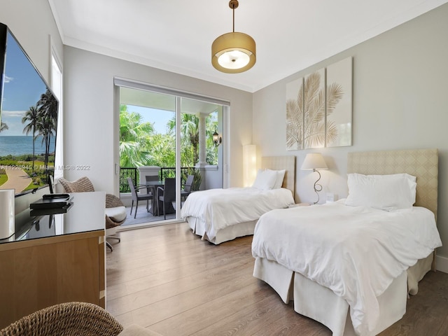 bedroom with crown molding, wood-type flooring, access to exterior, and a water view