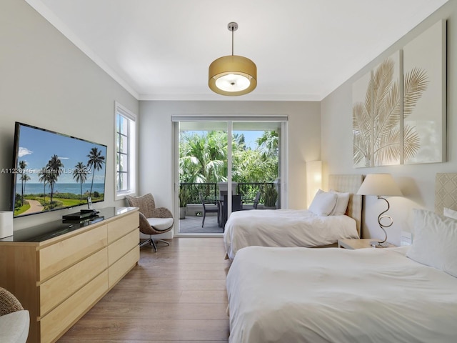 bedroom with a water view, ornamental molding, hardwood / wood-style floors, and access to outside