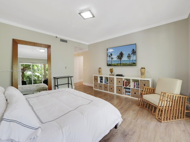 bedroom with ornamental molding and light wood-type flooring