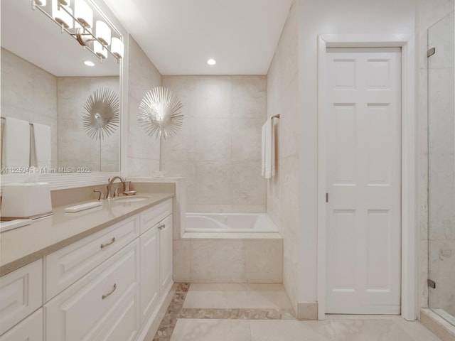 bathroom with a relaxing tiled bath, vanity, tile flooring, and tile walls