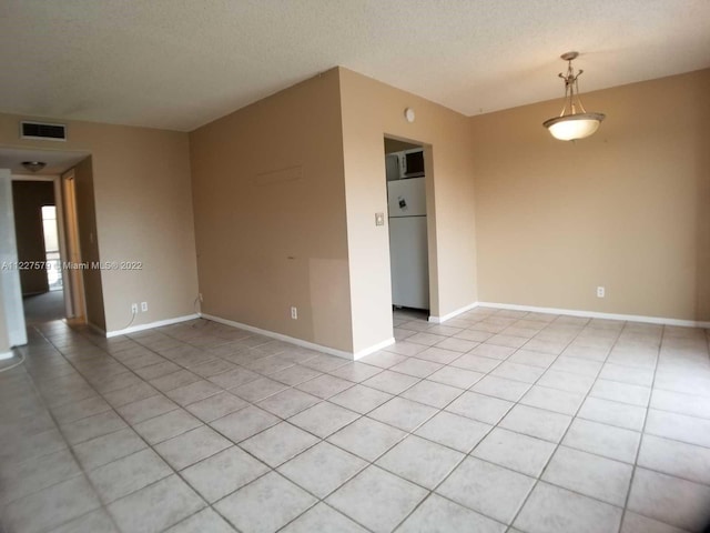 empty room featuring light tile floors and a textured ceiling