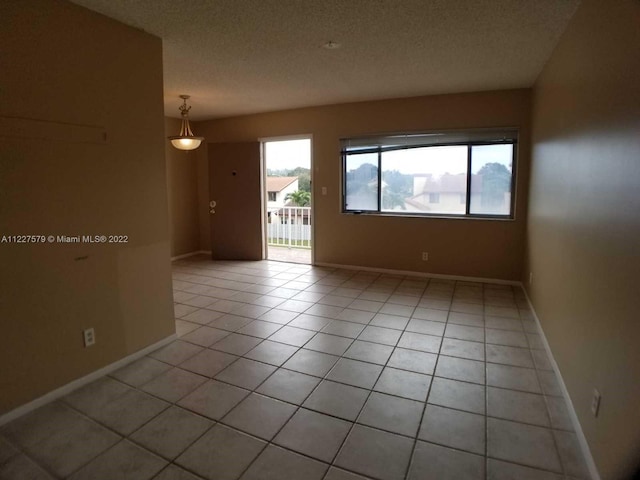 unfurnished room with a textured ceiling and light tile flooring