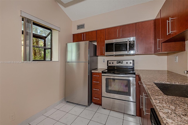 kitchen with dark stone countertops, appliances with stainless steel finishes, sink, and vaulted ceiling