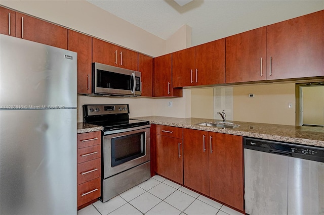 kitchen featuring light stone countertops, light tile flooring, sink, and stainless steel appliances