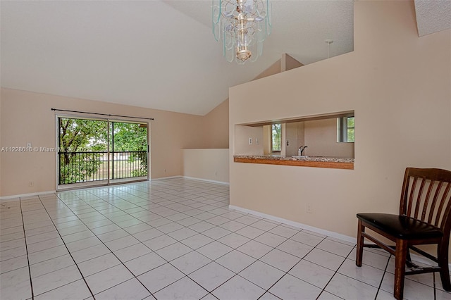 tiled empty room with a healthy amount of sunlight, a notable chandelier, and high vaulted ceiling