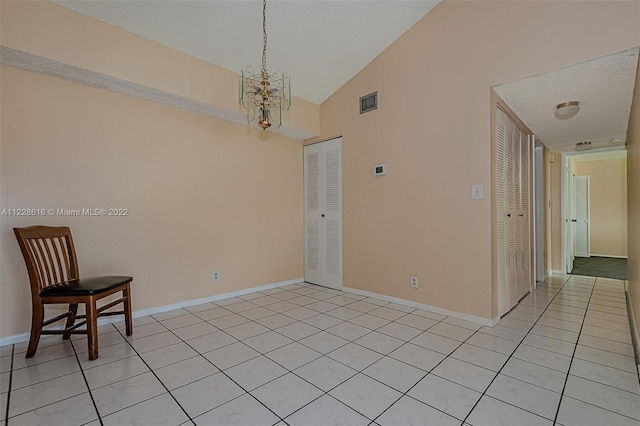 tiled empty room featuring high vaulted ceiling and a chandelier