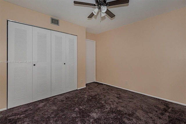 unfurnished bedroom featuring dark carpet, a closet, and ceiling fan