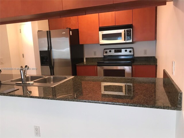 kitchen with sink, appliances with stainless steel finishes, and dark stone countertops