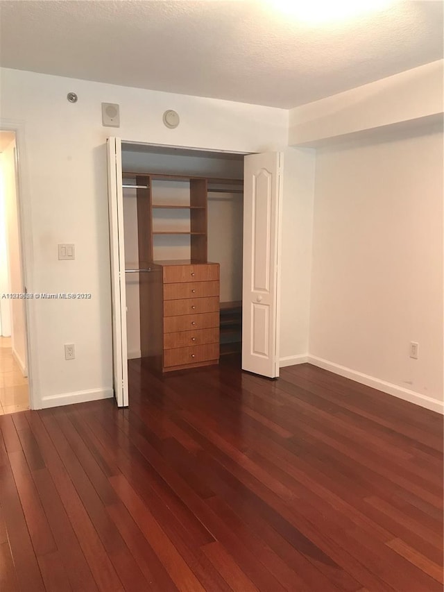 unfurnished bedroom with a closet and dark hardwood / wood-style flooring