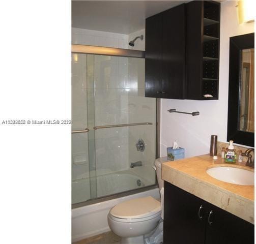 full bathroom featuring vanity, enclosed tub / shower combo, and toilet