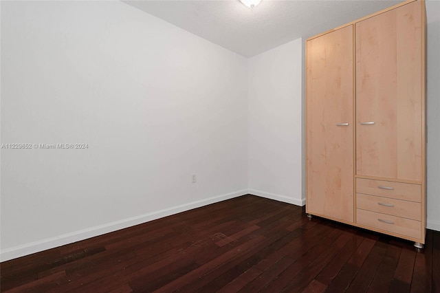 unfurnished bedroom featuring a closet and dark wood-type flooring