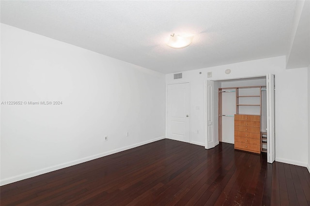 unfurnished bedroom featuring dark wood-type flooring, a textured ceiling, and a closet