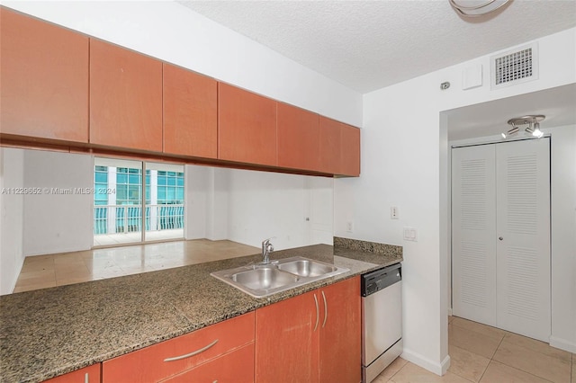 kitchen featuring sink, dishwasher, a textured ceiling, dark stone counters, and light tile patterned floors