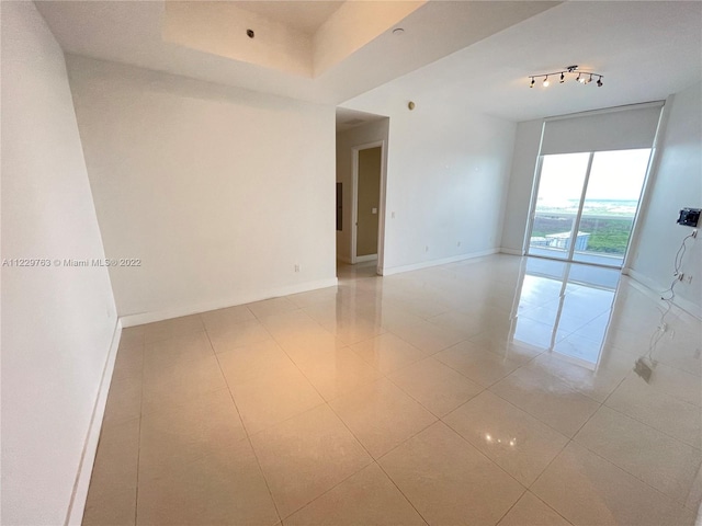 unfurnished room with track lighting and light tile floors