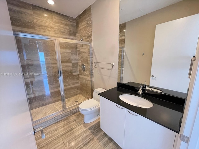 bathroom with vanity, tile floors, a shower with shower door, and toilet