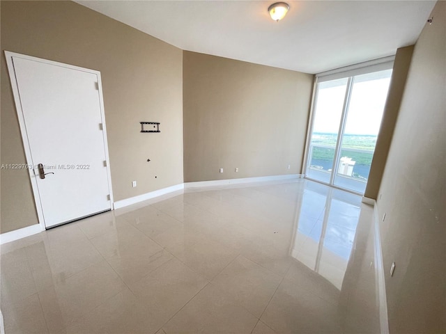 unfurnished room with light tile flooring and a wall of windows