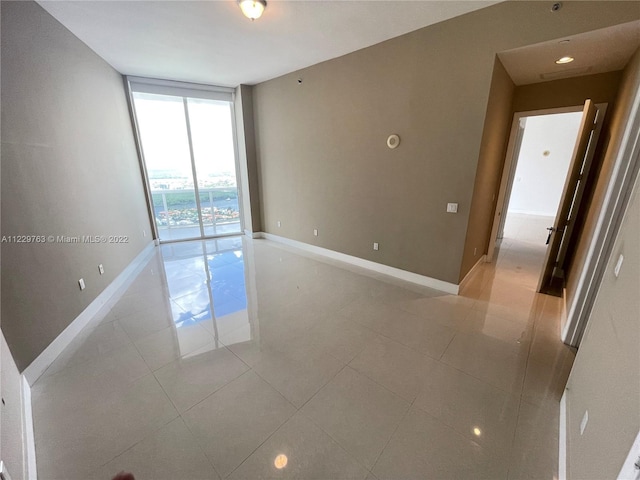 tiled spare room featuring a wall of windows