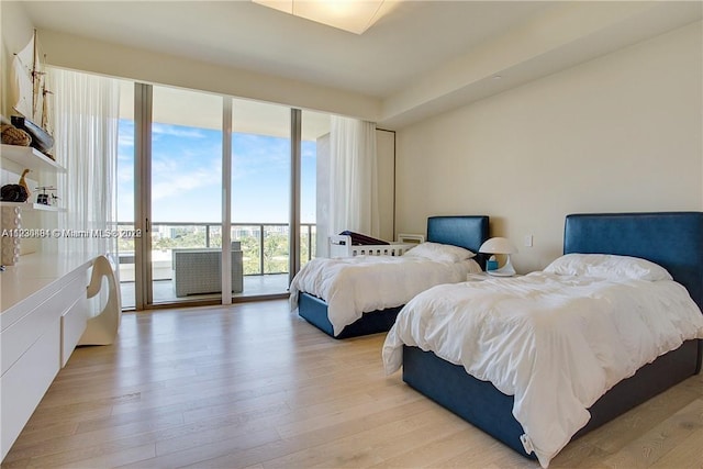 bedroom featuring a wall of windows, access to exterior, and light hardwood / wood-style flooring