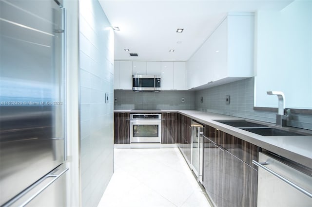 kitchen with white cabinetry, light tile flooring, appliances with stainless steel finishes, sink, and tasteful backsplash