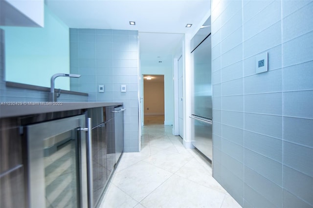 bathroom with wine cooler, vanity, tile flooring, and tile walls