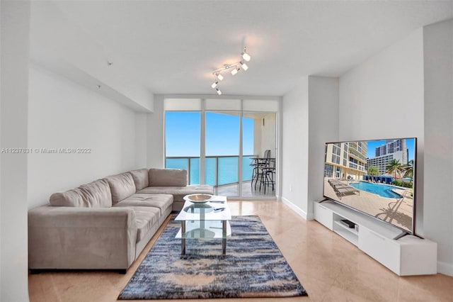 living room featuring floor to ceiling windows, rail lighting, a water view, and light tile floors