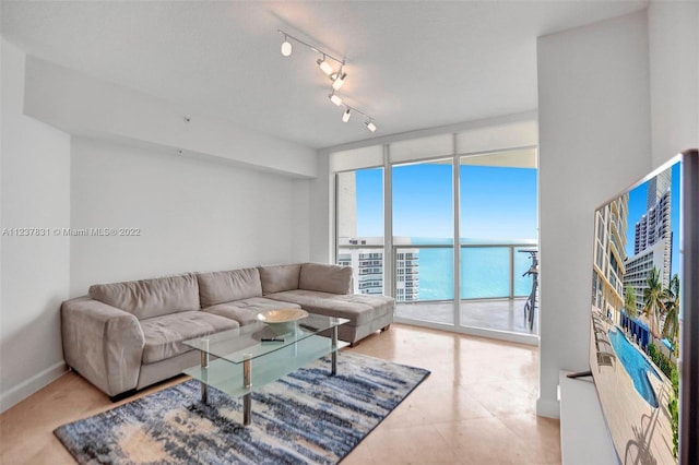 living room featuring track lighting, a wall of windows, and a water view