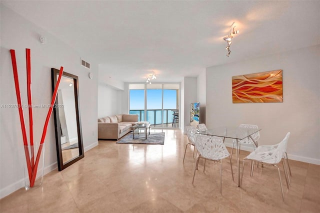 dining space with light tile floors, track lighting, and floor to ceiling windows