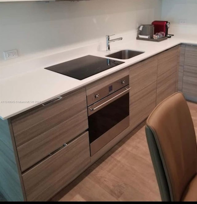 kitchen with light hardwood / wood-style flooring, sink, black electric stovetop, and stainless steel oven