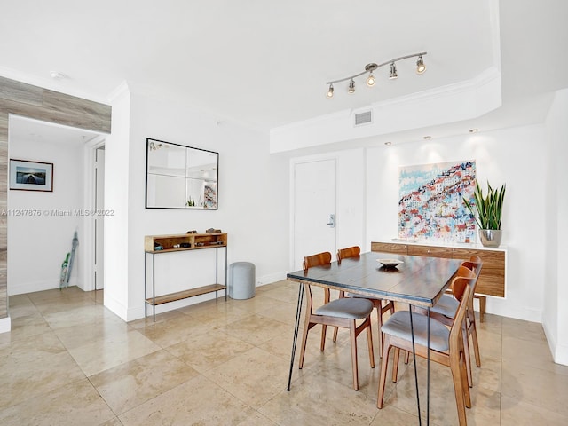 tiled dining room featuring rail lighting and crown molding