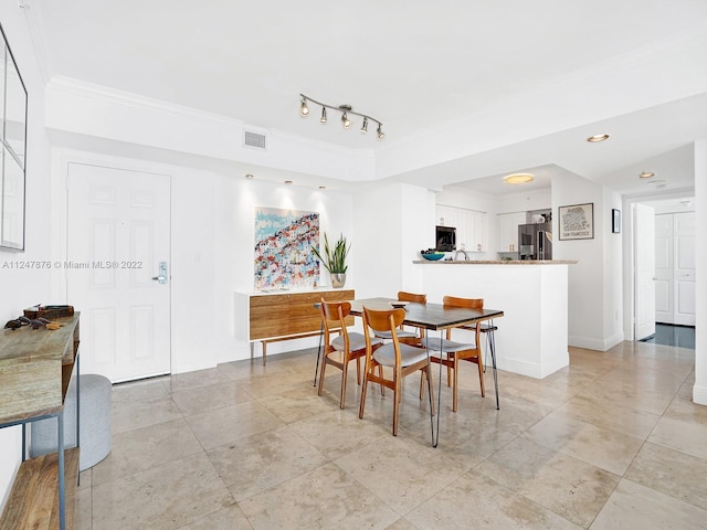 tiled dining space featuring crown molding and track lighting