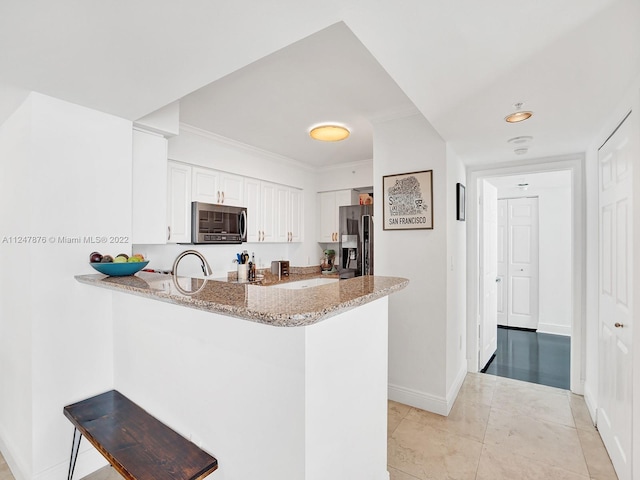 kitchen with light tile floors, a kitchen breakfast bar, appliances with stainless steel finishes, light stone countertops, and white cabinetry