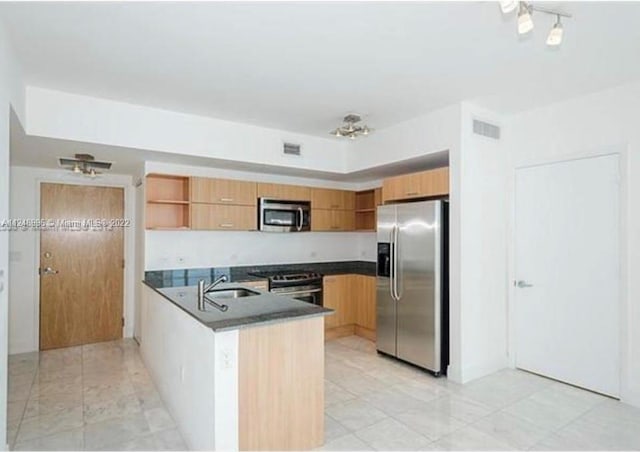 kitchen with light tile flooring, kitchen peninsula, appliances with stainless steel finishes, sink, and track lighting