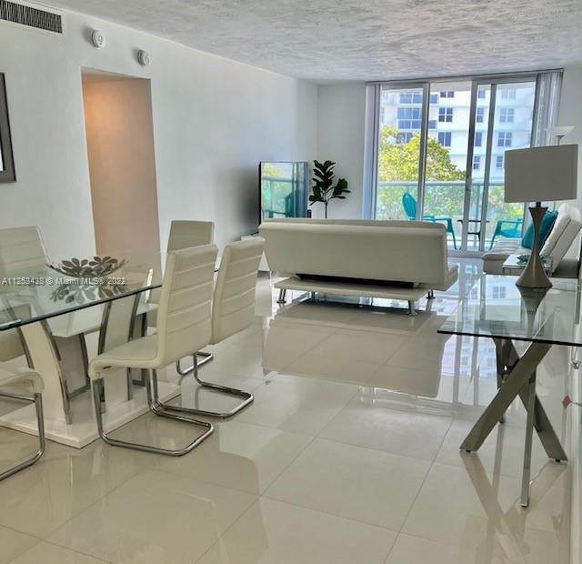 dining area with a textured ceiling, a wall of windows, and light tile floors