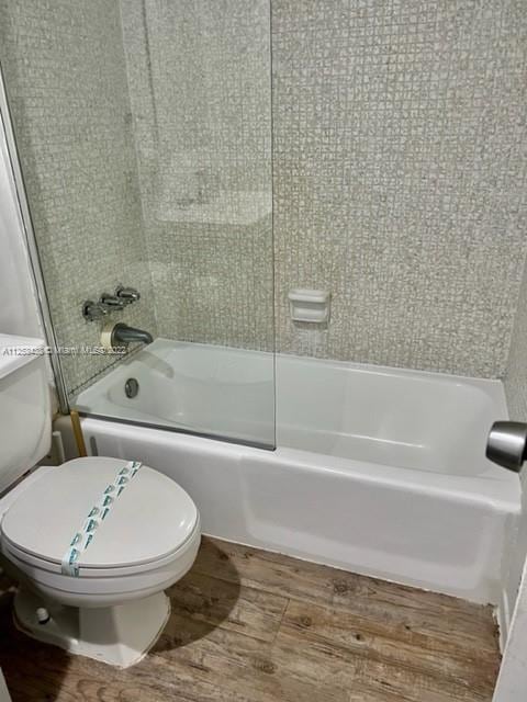 bathroom with hardwood / wood-style flooring, toilet, and enclosed tub / shower combo