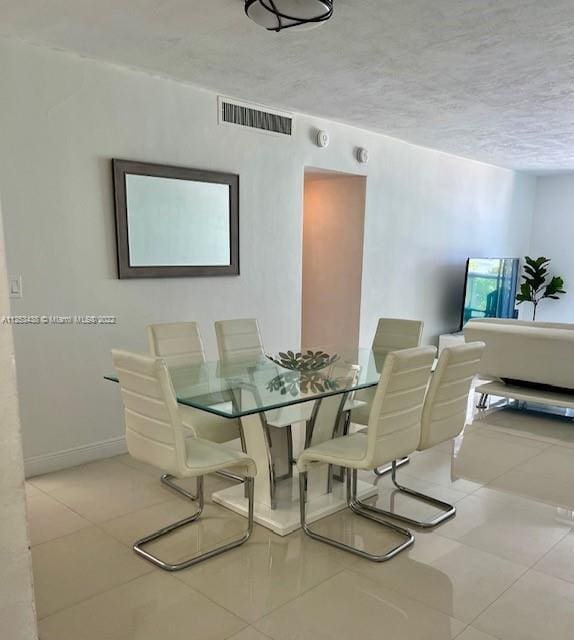 tiled dining space with a textured ceiling