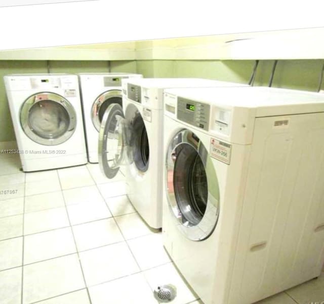 clothes washing area with light tile floors and washing machine and clothes dryer