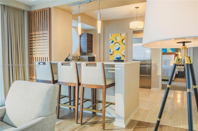 kitchen featuring kitchen peninsula, pendant lighting, and light hardwood / wood-style flooring