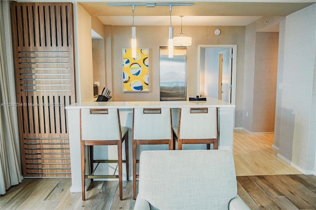 kitchen featuring a breakfast bar area, pendant lighting, and light hardwood / wood-style flooring