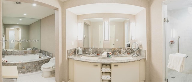 bathroom with tiled tub, double vanity, and toilet