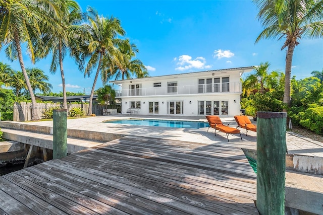 back of property featuring a balcony, a fenced in pool, and a patio area