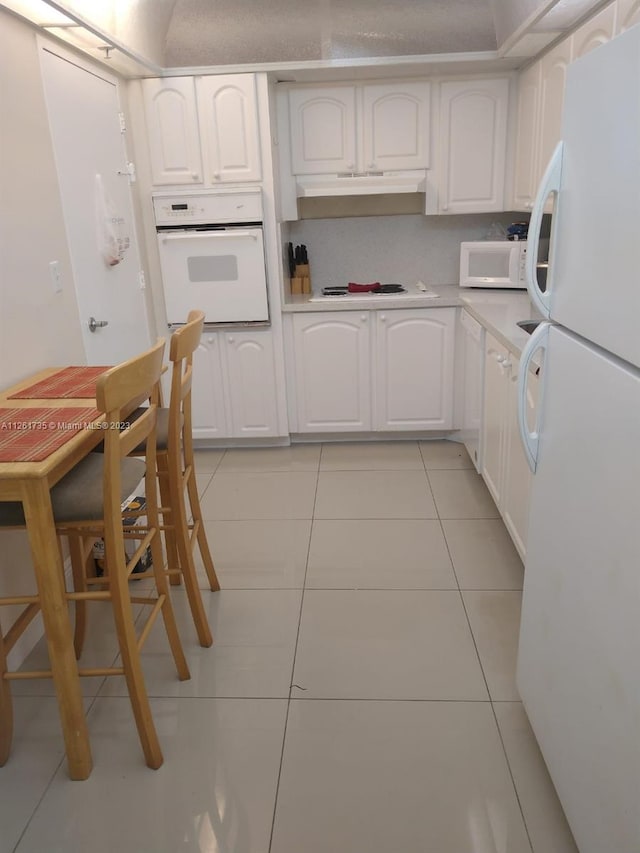 kitchen with light tile floors, white appliances, and white cabinetry