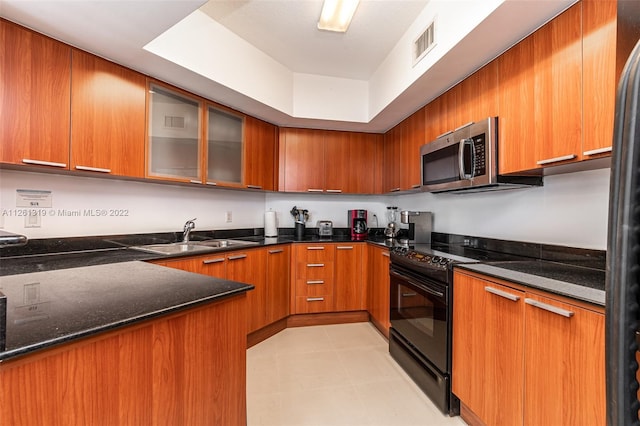 kitchen with black electric range oven, refrigerator, sink, and dark stone counters