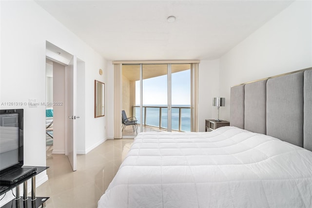 bedroom featuring expansive windows, a water view, and access to exterior