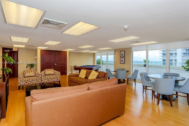 living room with light hardwood / wood-style floors, a wall of windows, and pool table